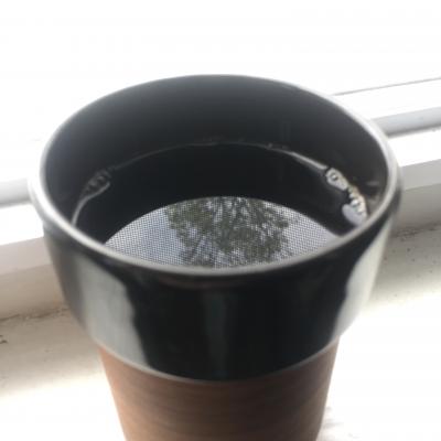 cup of coffee reflecting a tree and sky